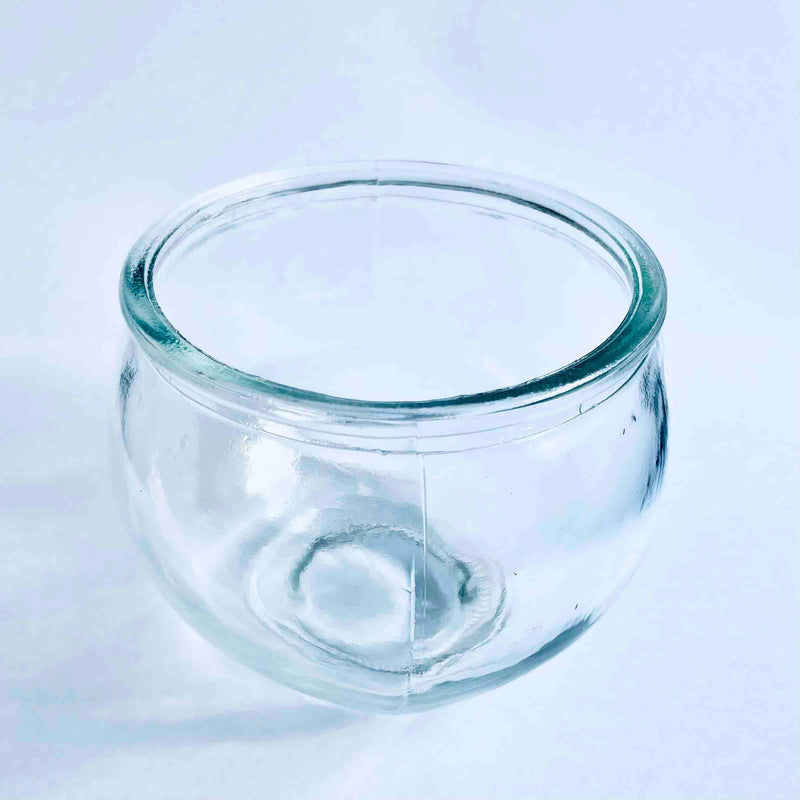 Transparent round glass candle holder with thick rim on white surface