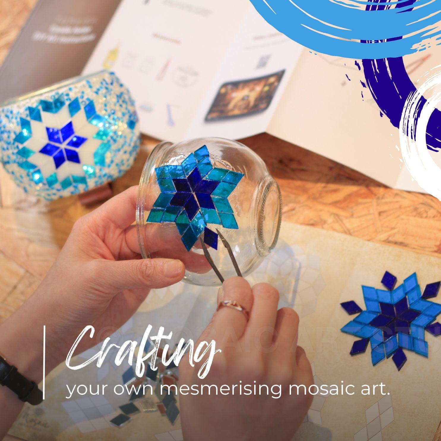 Hands crafting blue mosaic star pattern on glass candle holder with mosaic art kit and instructions
