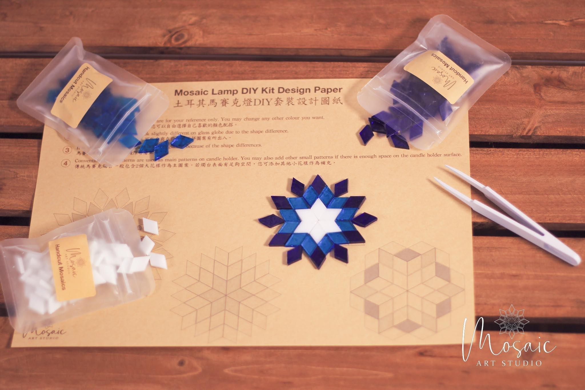 Mosaic lamp DIY kit with blue and white handcut glass pieces on design paper and wooden table