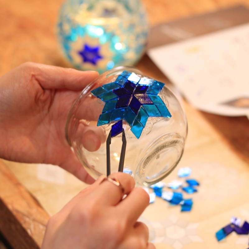 Hands placing a blue glass star on the globe
