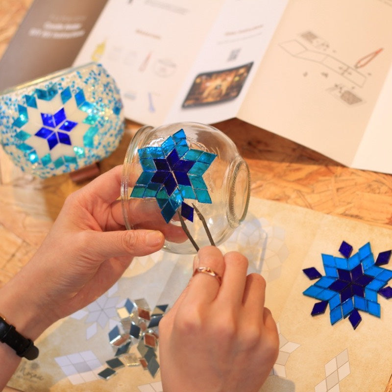 Hands placing the first glass pieces, instructions open beside them