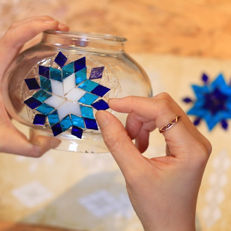 Hands pressing glass pieces into a star pattern