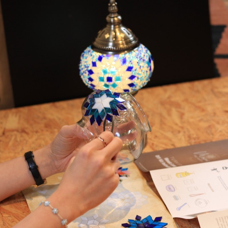 A finished blue mosaic lamp glowing on the table