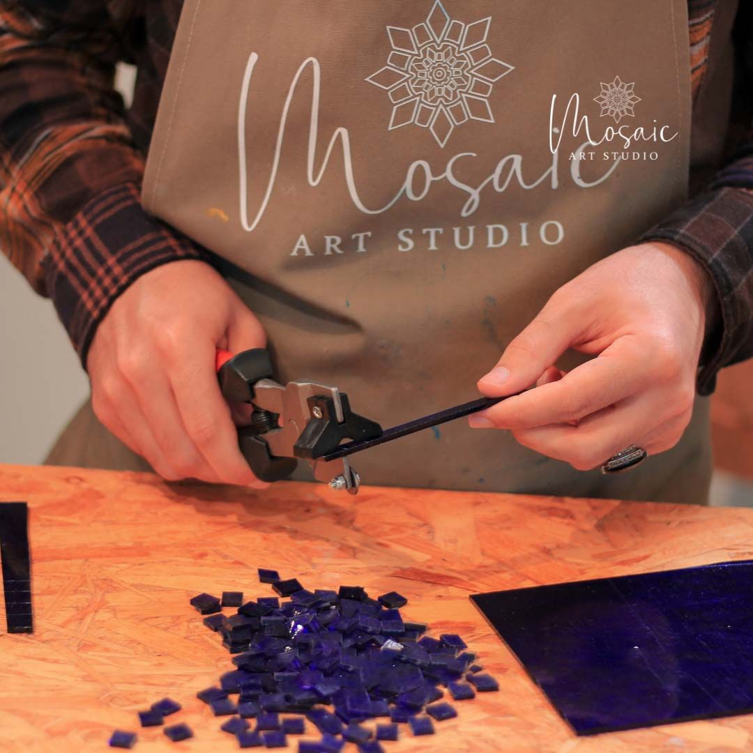 Artisan hand-cutting glass mosaics at Mosaic Art Studio